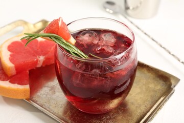 Tasty cocktail with grapefruit, ice cubes and rosemary on white table, closeup