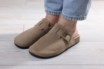 Woman in stylish beige slippers on light wooden floor, closeup