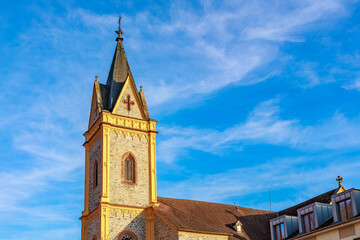 Historic church tower against bright blue sky with wispy clouds