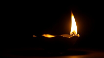 A golden oil lamp glows warmly against a dark backdrop, its flickering flame creating a cozy atmosphere.
