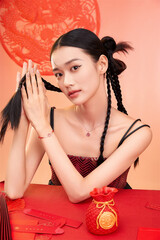Young woman with braided hair poses with a decorative red background Chinese word means bless.
