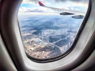 View of a sprawling cityscape from an airplane window during a daytime flight over urban landscapes