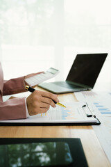 Fototapeta premium A professional businesswoman reviews financial documents using a calculator, pen, and laptop in the office, analyzing reports, charts, and graphs to manage budget, expenses, investment, and strategic 