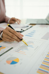 A professional businesswoman reviews financial documents using a calculator, pen, and laptop in the office, analyzing reports, charts, and graphs to manage budget, expenses, investment, and strategic 