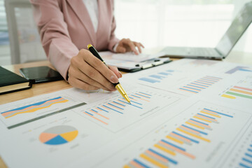 A professional businesswoman reviews financial documents using a calculator, pen, and laptop in the office, analyzing reports, charts, and graphs to manage budget, expenses, investment, and strategic 