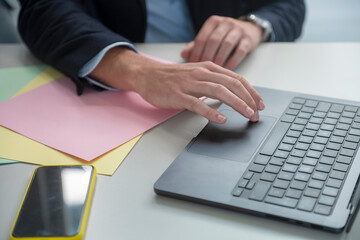 Obraz premium Businessman working on laptop in modern office with colorful documents