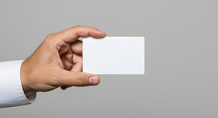 Obraz premium Professional hand presents a pristine blank card against a minimalist grey backdrop awaiting personalized branding and