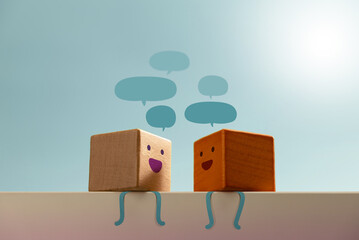 Smiling wooden blocks engage in conversation with speech bubbles. reflects friendly communication...