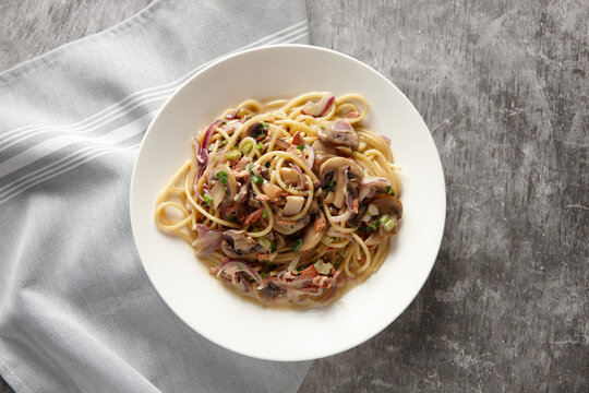 Spaghetti carbonara loaded with meat and served in a white plate.