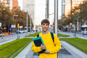 Smiling college student holding books and walking in city center