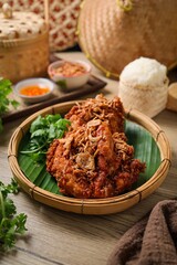 Fried chicken topped fried shallots with sticky rice and thai sauce in banana leaf on wooden background, thai called kai tod hat yai