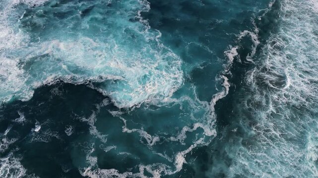 Aerial view of the ocean's turbulent surface, with white foamy waves contrasting against the deeper turquoise waters, Porto Formoso, Azores, Portugal.
