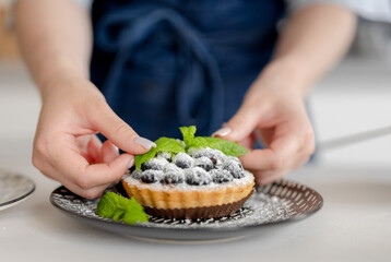 Girl Decorating Blueberry Dessert With Mint Leaves