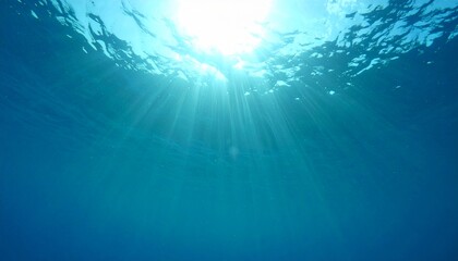 Obraz premium Sunlight beams penetrate deep blue ocean surface creating serene view