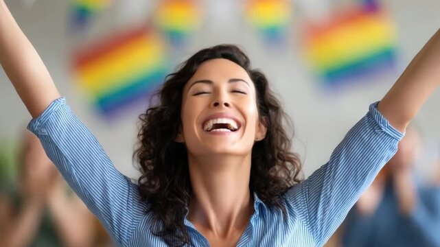 Joyful woman with curly hair smiling and raising arms celebration, happy and proud with rainbow pride flag background, LGBTQ acceptance and inclusivity indoor event, expressing support and cheerful