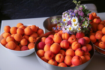 Ripe, juicy apricots in bowls and a bouquet of wildflowers made of daisies, clover, and other flowers