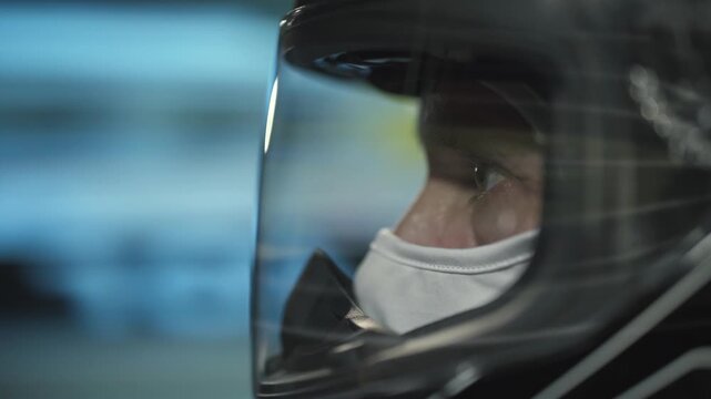 Racing driver captured in motion, intense eyes visible through the helmet as he speeds.