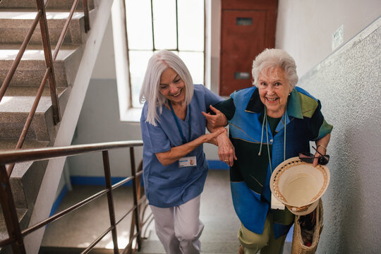 Female healthcare worker helping senior patient walking up the stairs. - Powered by Adobe