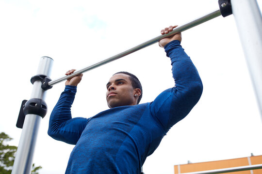 Young Indigenous man doing pulls ups at outdoor park
