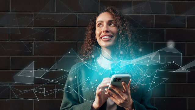 Woman smiling while using smartphone against dark brick wall with digital effects in modern urban setting - Powered by Adobe