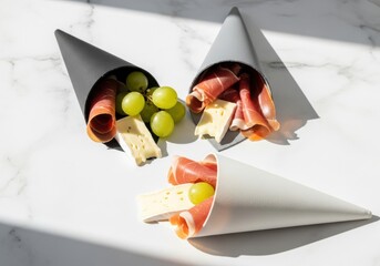 Photo of modern charcuterie cones filled with prosciutto, cheese, and grapes, offering a stylish and individual serving for parties and events