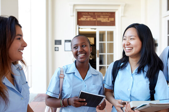 Three High School friends laughing whilst checking their mobile phones