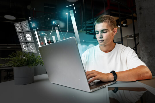 Young adult analyzing data on a laptop in a modern workspace during daytime near urban center