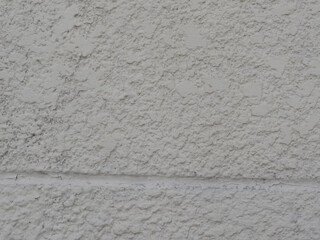 Close up of textured white wall surface showing rough, uneven finish and subtle cracks, creating rustic and weathered appearance