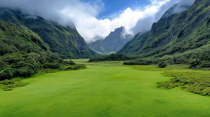 Naklejka premium Lush green valley surrounded by majestic mountains and clouds, offering serene atmosphere