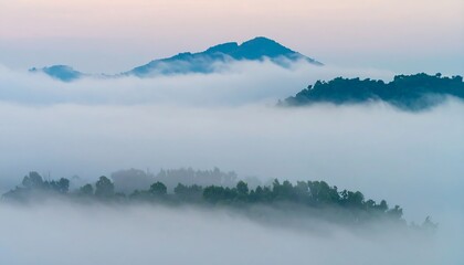 Fototapeta premium Misty mountain landscape, featuring layered hills veiled in soft, pastel-hued clouds, showcasing a tranquil and serene atmosphere.