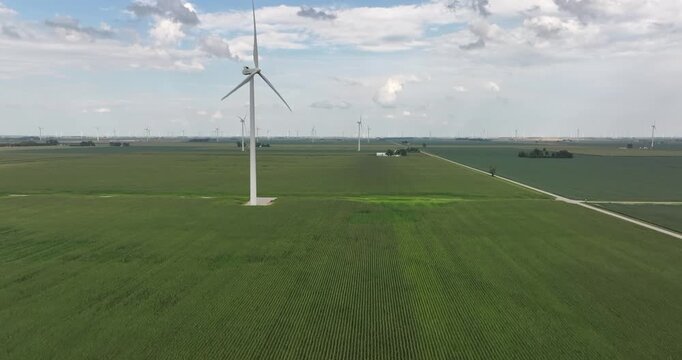Aerial view of wind turbines standing tall in green fields under a partly cloudy sky, a scene of renewable energy generation, Monroeville, Indiana, United States.