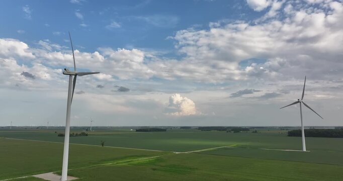 Aerial view of wind turbines standing tall in a vibrant green field under a cloudy sky, capturing the essence of sustainable energy, Monroeville, Indiana, United States.