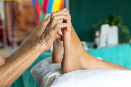 Reflexology treatment showing hands massaging feet at markets