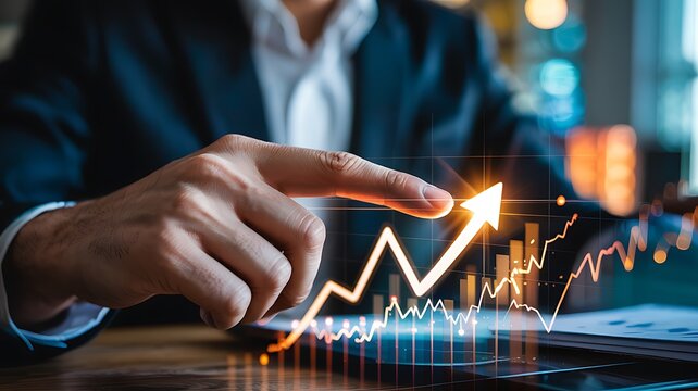 Close up of a businessman s hand pointing at a glowing upward trending financial stock market graph on a digital tablet screen