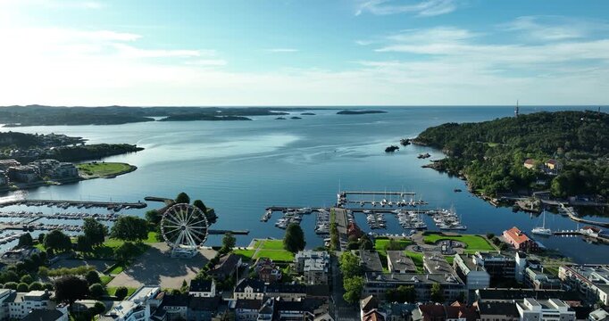 A stunning coastal landscape showcases a lively harbor with a prominent ferris wheel in Kristiansand.