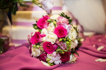 Floral beauty steals the spotlight as a lush bouquet of pink and white roses rests gracefully on a draped fabric. Soft petals hint at a joyful celebration, surrounded by elegant decor.