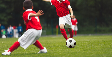 Dynamic Youth Soccer Game: Young Players in Red Jerseys Compete for the Ball on Green Grass Field