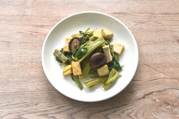 fried slice morning glory with tofu topping black mushroom in soy sauce on plate