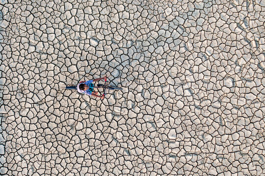 Chattogram, Bangladesh - 18 December 2019: Aerial view of a lone cyclist traversing the arid expanse, the intricate cracks of the parched earth creating a mesmerizing mosaic.