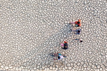 Chattogram, Bangladesh - 18 December 2019: Aerial view of figures traversing a parched landscape, the cracked earth a mosaic of stark whites and shadows.