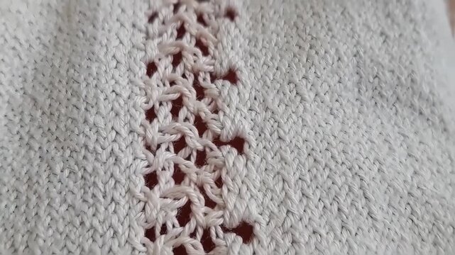 Close-up of a textured, light gray knitted fabric with a decorative pattern
