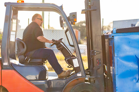 Forklift operator using machinery to move industrial bins around site