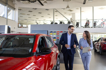 Confident sales team in dealership, two beautiful consultants or managers in black full suit with crossed arms looking on camera