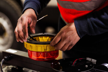 Male mechanic working on set of wires attached to dual-coloured light fixture