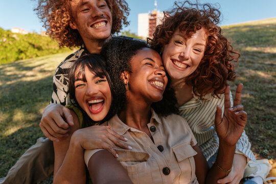 Happy friends embracing and smiling outdoors in a park