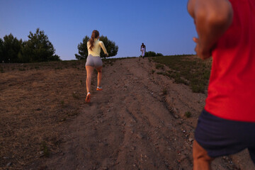 Fitness friends running uphill at sunset