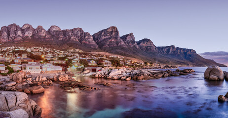 Panorama long exposure: Bakoven beach lit up after sunset, Cape Town, South Africa