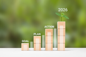 Business growth success achievement concept. Plan, goal and action to achieve success in 2026. Wooden blocks in form of graphical steps up and young green seedling of business growth process.