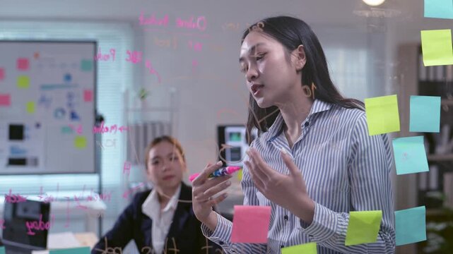 A woman is giving a presentation in front of a whiteboard with a lot of colorful sticky notes