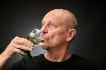 Closeup portrait of a senior man tasting a good white wine